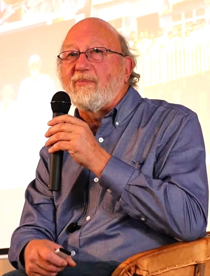 A portrait of the ethnopharmacologist Dennis McKenna speaking at a symposium.